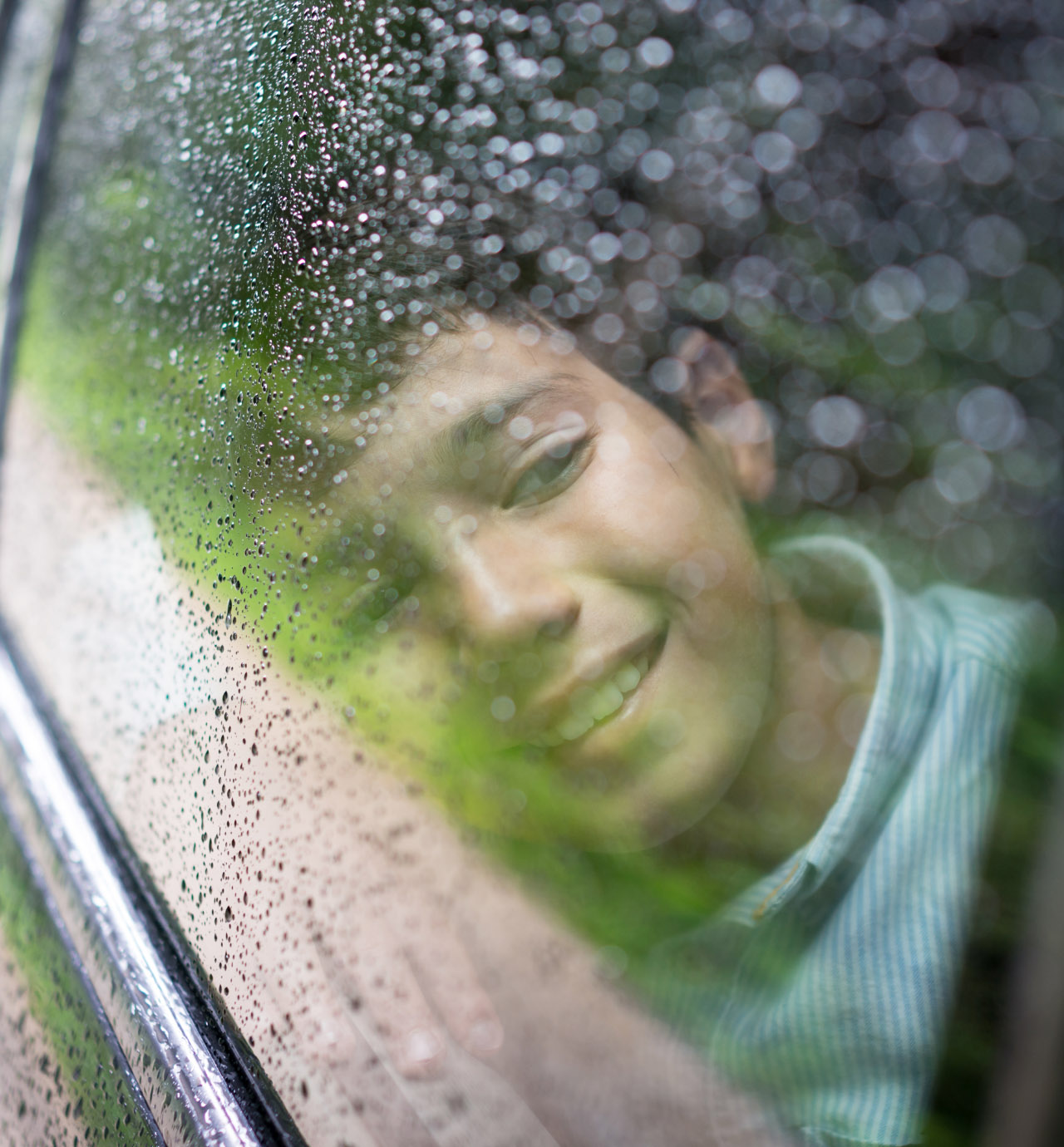 Niño sonriendo a través de la ventana de un carro.