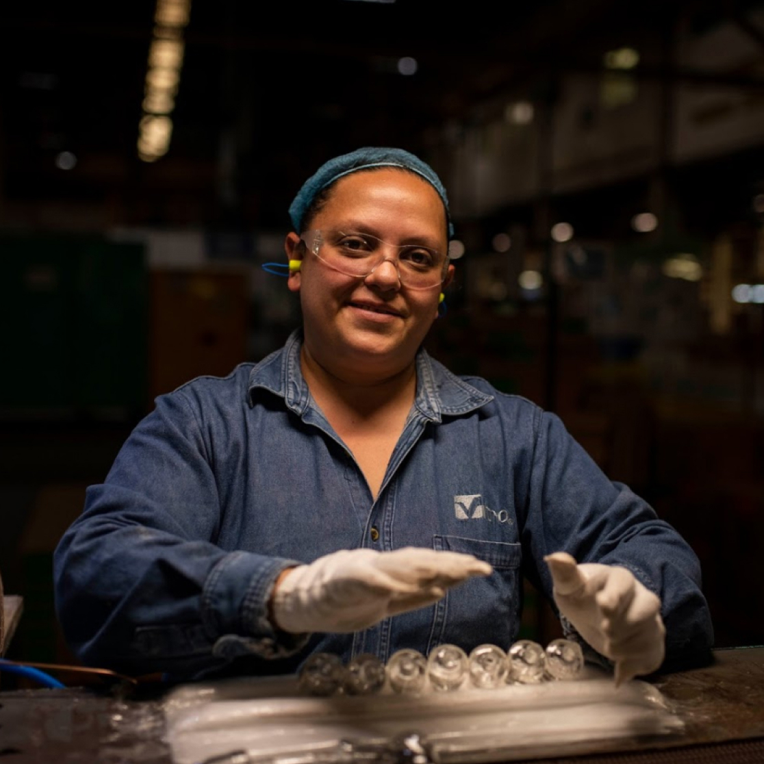 Mujer en línea de producción de envases de vidrio.